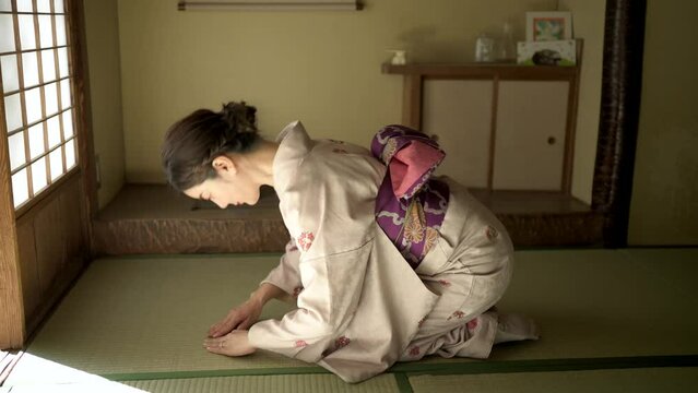 和室に正座して丁寧にお辞儀をする着物姿の女性