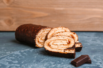 Pieces of delicious sponge cake roll and chocolate on grey table