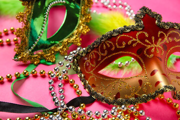 Carnival mask for Mardi Gras celebration with feathers and beads on pink background, closeup