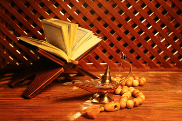 Aladdin lamp of wishes, prayer beads and Koran for Ramadan on wooden table