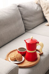 Fototapeta na wymiar Board with geyser coffee maker, cup of espresso and cookies on sofa