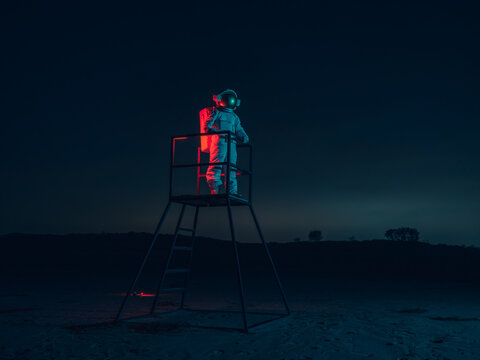 A lone astronaut stands on a tower