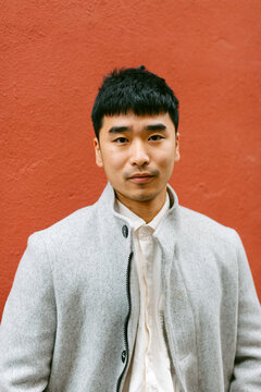 Portrait of Elegant handsome man over red wall looking at camera