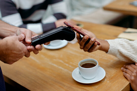 Anonymous hands paying the bill of cafeteria with mobile phone