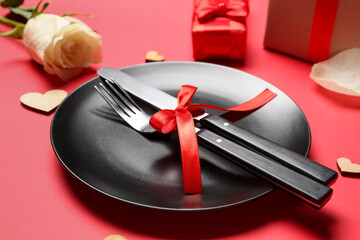 Table setting with tied cutlery on red background. Valentine's Day celebration