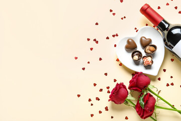 Bottle of wine, chocolate candies and rose flowers on beige background. Valentine's Day celebration
