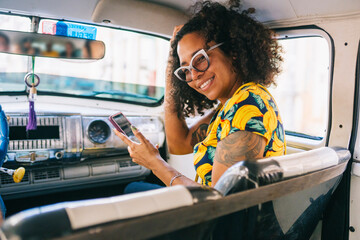 An afro woman inside a taxi with a phone
