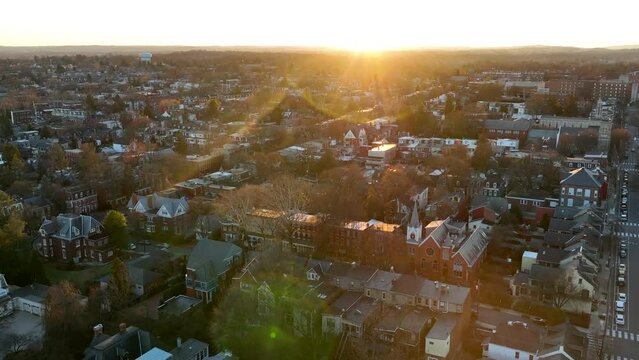 Aerial orbiting shot of golden hour sunset over American city. Housing in USA urban, metro area during beautiful sunrise in winter.