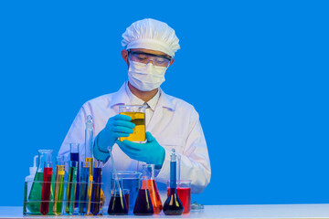 Experienced chemist wearing a uniform hand holding and looking at a bottle with chemical substance, with blue light isolate