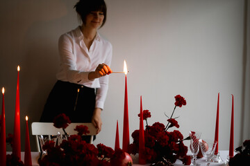 Woman lights a candle on holiday table setting
