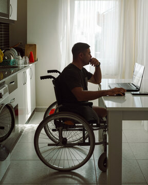 Disabled man using laptop while sitting in wheelchair