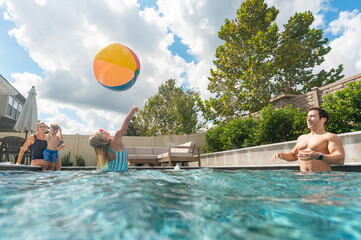 Family of four playing with beachball in pool