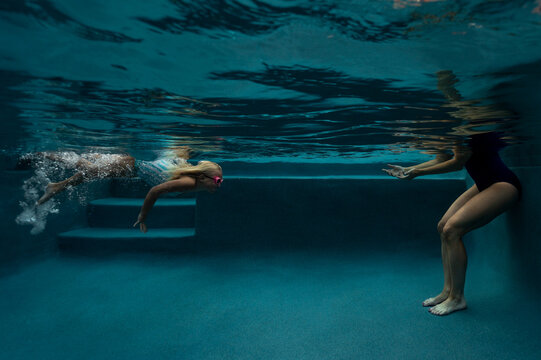 A girl swims to her encouraging mother