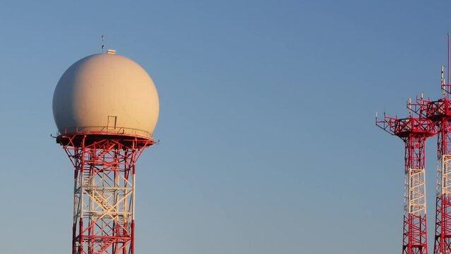 Panning shot from a radar dome to triple antennas at the Alicante-Elche international airport. Sunset light.