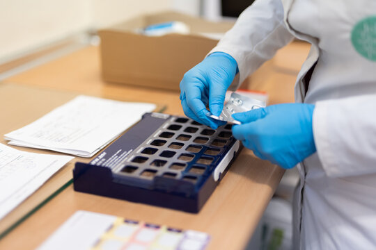 pharmacist woman putting pills into pill box