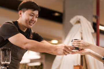 Asian man, coffee maker, handing over a cup of coffee Served to female customers counter, Startup Business Concept.