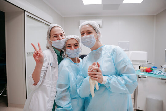 The surgeon and the interns are standing in the operating room