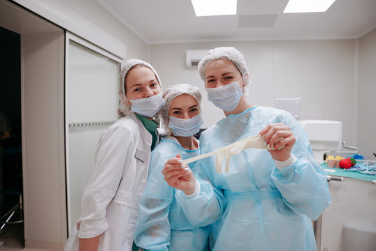 The surgeon and the interns are standing in the operating room