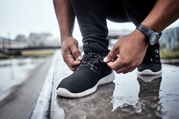 Fitness, shoes and running with a sports man tying his laces for an outdoor cardio or endurance workout. Exercise, footwear and training with a male athlete or runner fastening his shoelaces outside