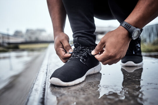 Fitness, shoes and running with a sports man tying his laces for an outdoor cardio or endurance workout. Exercise, footwear and training with a male athlete or runner fastening his shoelaces outside