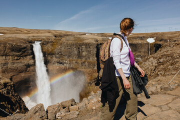 Traveler woman looking on A Huge Waterfall In Iceland with rainbow
