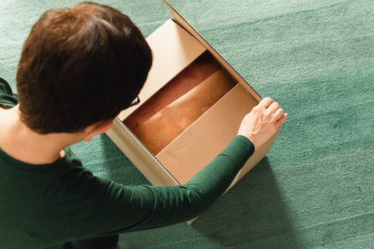Middle-aged adult woman opening clothing delivery box
