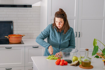 young girl cutting lettuce to prepare a salad