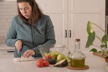 young girl cutting goat cheese to prepare a salad