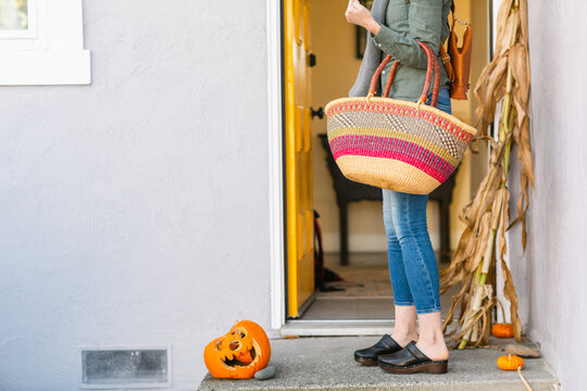 Crop woman leaving home with shopping bag