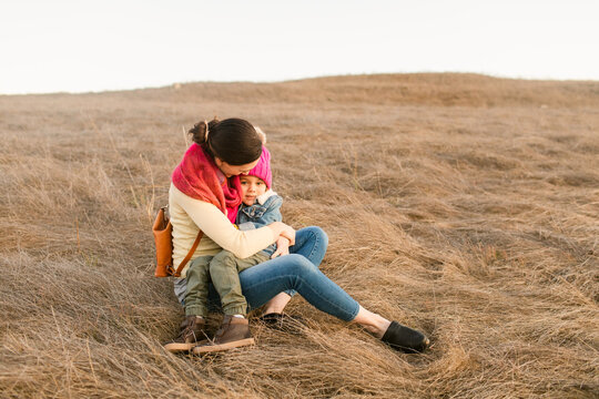 Mom and son hugging sitting at field
