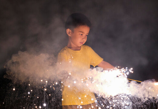 Asian little boy, playing with firework at night in nature outdoors