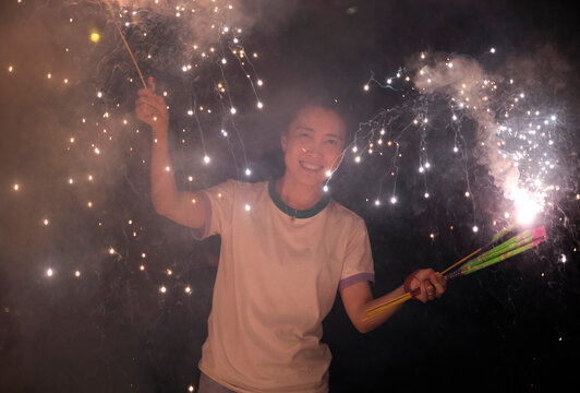 Asian Woman, Playing Fireworks Outdoors At Night In Nature