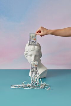 Statue with cut dollar banknote held by woman.