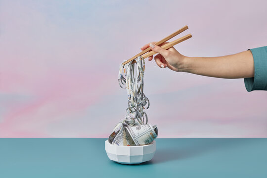 Dollar noodles taken by woman's paper chopsticks.