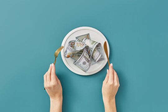 Dollars on plate, woman's hands holding cutlery.