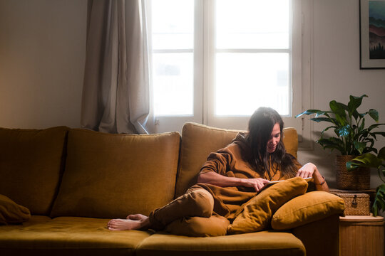 Woman browsing internet with tablet on the sofa