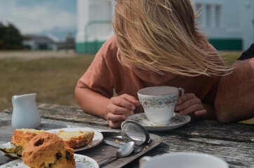 A blond boy drinking tea outdoor