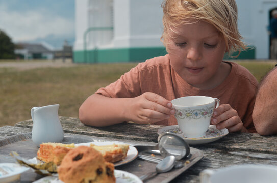 A blond boy drinking tea outdoor