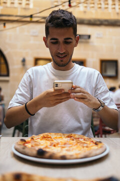 Young man taking a picture of his food before eating