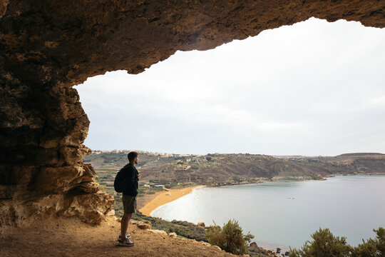 Man in the Tal-Mixed cave in Malta viewing the Ramla bay