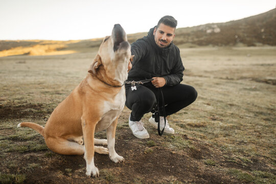 dog howling in nature next to its owner