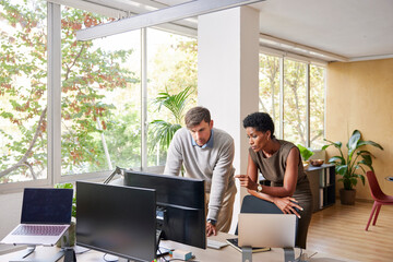 Focused diverse colleagues analyzing data on PC