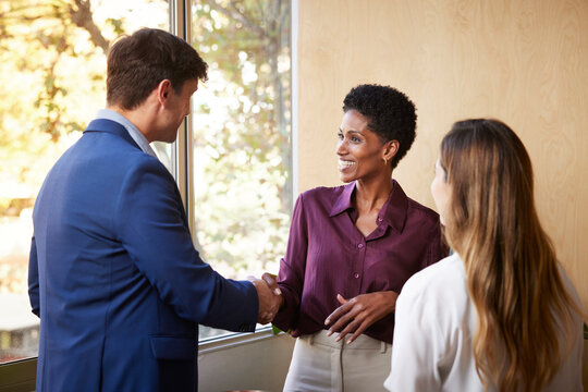 Black businesswoman greeting colleagues in office