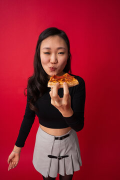 Cheerful Asian woman chewing pizza