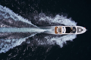Large yacht in motion top view. Large motor boat with an awning fast movement on dark water aerial...
