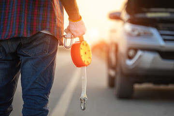 Man holding emergency car towing line and standing infront of car on the roadside. Car accident,...