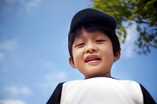 Asian little boy looking down camera outdoors 