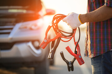 Man holding red and black battery cable for charging the car. Car Repair and maintenance concept
