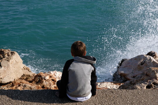 boy watching the splashes of the sea 