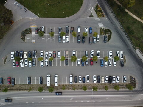 Busy large modern carpark with symmetrical roads rows of parking bays lots of symmetry and colours aerial view from drone up above looking down.